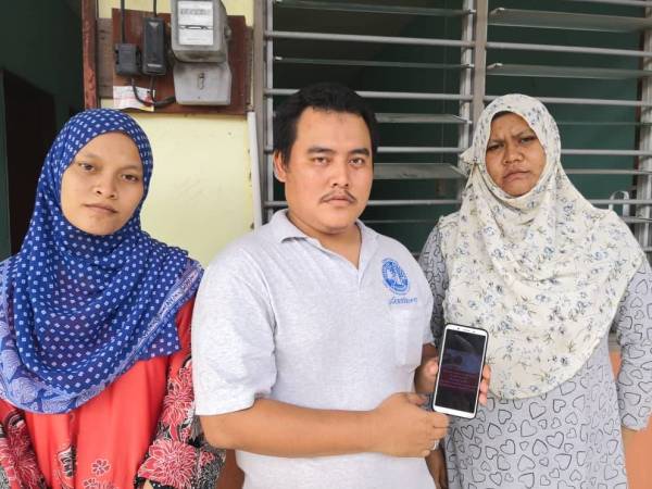 Ahmad Pauzi bersama isterinya (kanan) dan adiknya menunjukkan video dikongsi ibunya sebelum terbabit dalam kemalangan di Jalan Parit 7 Ban 2 pada Isnin lalu.