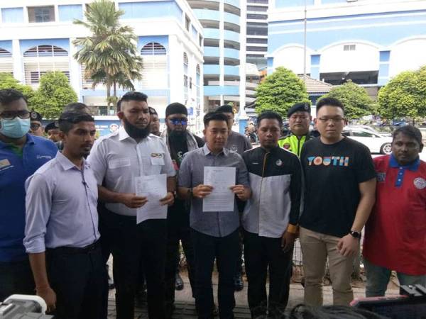 Muhammad Azri (dua kiri) bersama Pemuda BN dan Pas buat laporan berhubung kulit hadapan buku didakwa hina Jata Negara di Ibu Pejabat Polis Daerah Dang Wangi, hari ini.