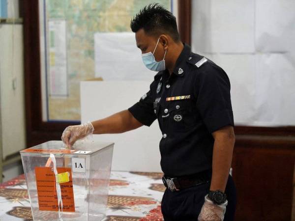 Koperal Muhamad Muhaidin memakai pelitup muka dan sarung tangan ketika mengundi awal bagi PRK DUN Chini di Balai Polis Chini hari ini. Foto: Bernama