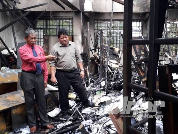 Mazlan (kiri) dan Pegawai Pejabat Pendidikan Daerah (PPD) Pasir Gudang, Kuswandi Tayen meninjau kesan kebakaran di tiga bilik di SMK Pasir Gudang 3, Pasir Gudang hari ini.