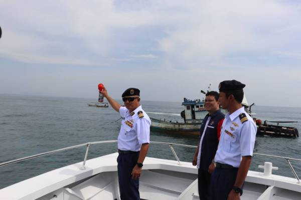 Muhammad Suffi (kiri) ketika operasi pelupusan bot nelayan Vietnam yang dilakukan di perairan Batu Buruk, Kuala Terengganu, hari ini.
