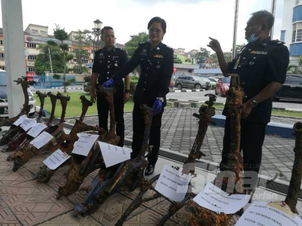 Shafa'aton (tengah) bersama rangka motosikal curi yang berjaya ditemui semula selepas dibuang ke dalam Tasik Biru, Kundang.