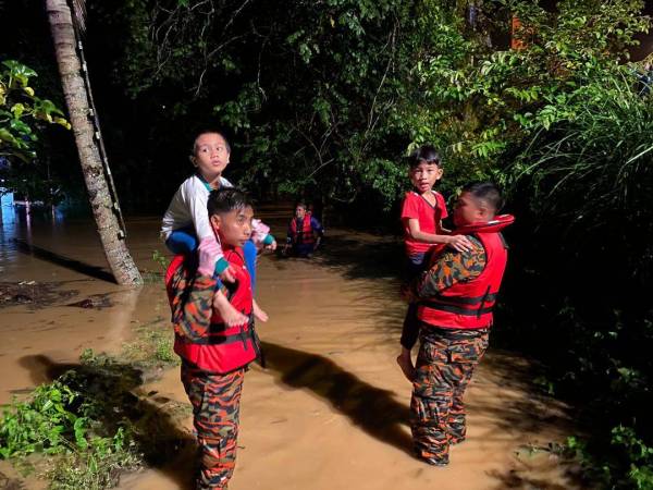 Anggota bomba memindahkan dua kanak-kanak yang terlibat dalam kejadian banjir kilat di Pengkalan Hulu, Perak sebentar tadi. - Foto JBPM Perak