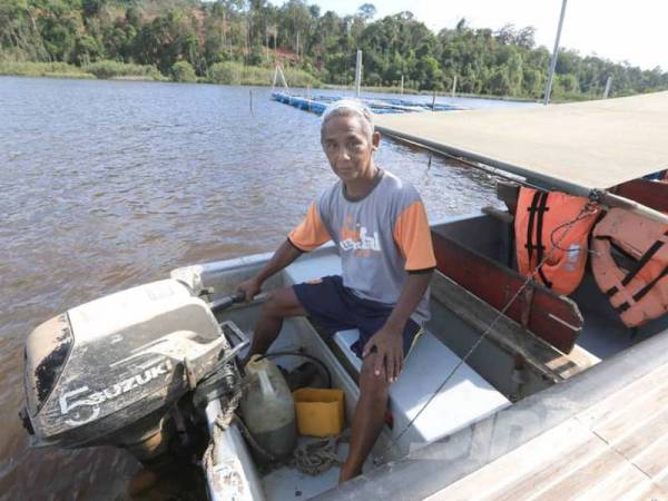 Awang bersama bot yang digunakan untuk membawa pelancong di Tasik Chini.