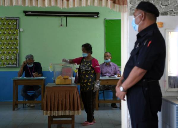 Seorang pengundi orang asli memakai sarung tangan ketika mengundi pada PRK DUN Chini dalam suasana norma baharu di Sekolah Kebangsaan Kinchir, hari ini. - Foto Bernama