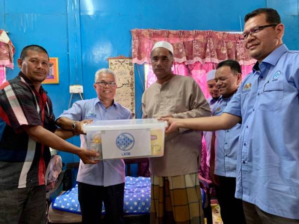 Othman (dua kiri) menyampaikan sumbangan makanan dan wang tunai kepada Hazahar ketika menziarahinya di Kedai Buloh hari ini.