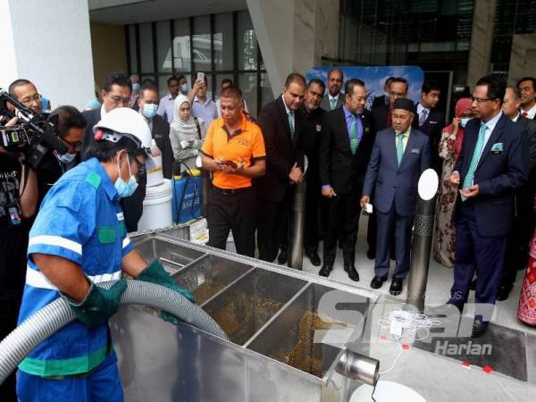 Narendran (lima dari kanan) bersama Tuan Ibrahim (dua dari kanan) meninjau operasi perkhidmatan pengosongan sistem perangkap FOG pada majlis pelancaran perkhidmatan itu di Kementerian Alam Sekitar dan Air, Putrajaya semalam. - Foto ASRIL ASWANDI SHUKOR