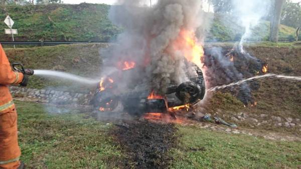 Anggota bomba memadamkan sebuah kereta yang terbalik dan terbakar di susur keluar Tol Pagoh, Johor hari ini.