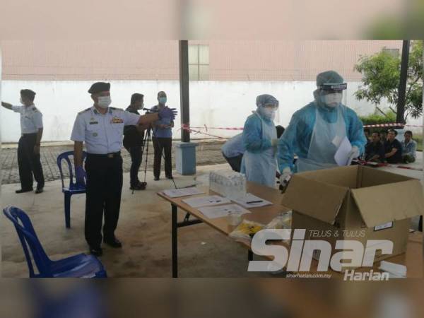 Muhammad Suffi (kiri) melihat proses saringan koronovirus (Covid-19) yang dilakukan kakitangan kesihatan daripada Pejabat Kesihatan Daerah Kuala Terengganu ke atas kesemua nelayan asing yang ditahan di pekarangan bangunan APMM Terengganu.