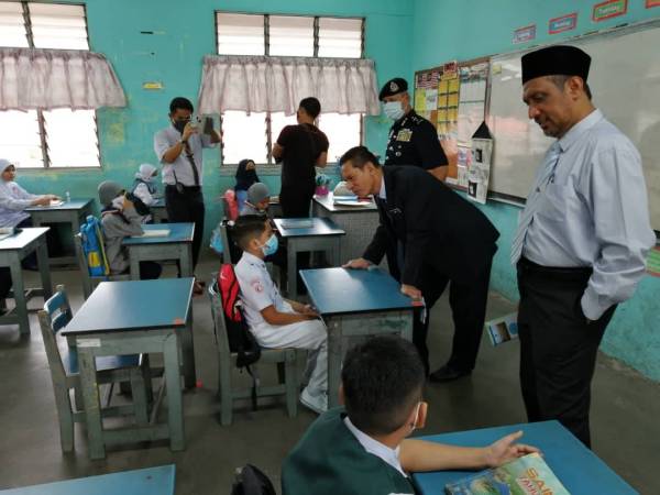 Zaimi (dua dari kanan) bertanya sesuatu kepada salah seorang murid ketika lawatan pemantauan pembukaan semula sekolah di SK Teruntum di Kuantan semalam.