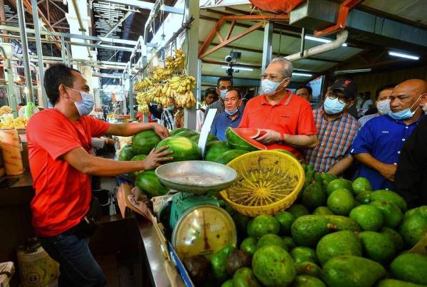 Annuar menyantuni peniaga di Pasar Raja Bot sewaktu sesi walkabout di pasar berkenaan pagi tadi.