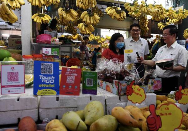 Chow Kon Yeow (kanan) membuat pembayaran melalui e-pembayaran di sebuah kedai buah-buahan di Kompleks Pasar dan Kemudahan Masyarakat Bayan Baru selepas melancarkan Inisiatif Tanpa Tunai di Pasar Awam seluruh negeri Pulau Pinang hari ini. -Foto Bernama