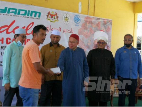 Dr Zulkifli (tengah) menyerahkan bantuan kepada seorang penerima pada Program YADIM Peduli Pasca Musa'adah Covid-19 di Kuala Terengganu hari ini.