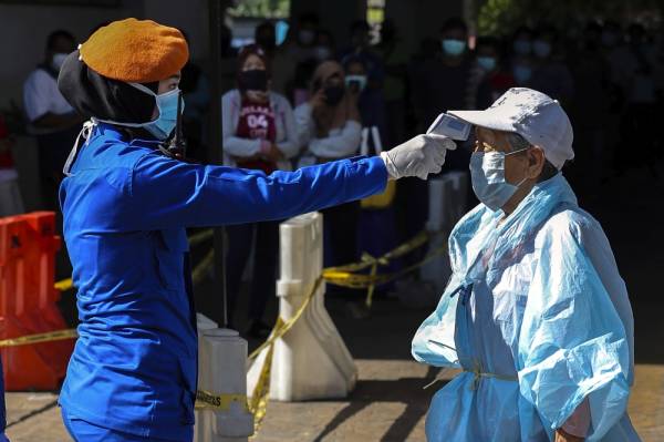 Anggota Angkatan Pertahanan Awam Malaysia (APM) memeriksa suhu badan warga emas yang hendak masuk ke Pasar Chow Kit. -Foto Bernama