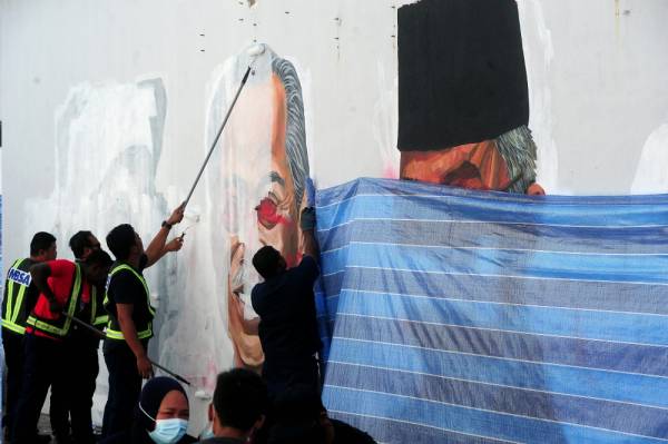 Kakitangan Majlis Bandaraya Shah Alam (MBSA) melakukan kerja-kerja memadam mural dan potret lukisan pemimpin negara yang diconteng oleh pihak tidak bertanggungjawab di Taman Cahaya Alam, Seksyen U12 hari ini. - Foto Bernama