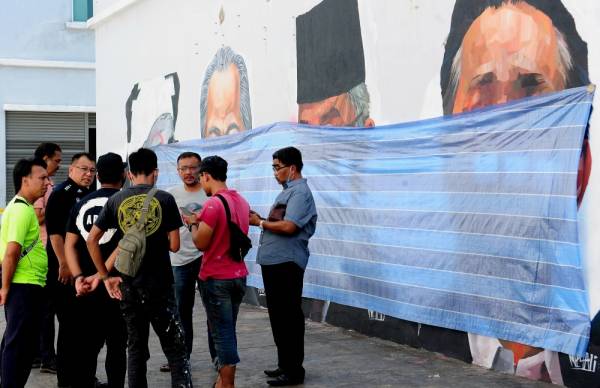 Pelukis, Muhammad Suhaimi Ali, Firdaus Nordin dan Abdul Hadi Ramli bersama pegawai polis berada di lokasi mural dan potret lukisan pemimpin negara diconteng di Taman Cahaya Alam, Seksyen U12 hari ini. -Foto Bernama