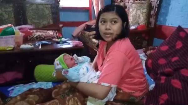 Heni memangku anak ketiganya yang dilahirkan secara tiba-tiba pada Sabtu lalu. - Foto: Agensi 