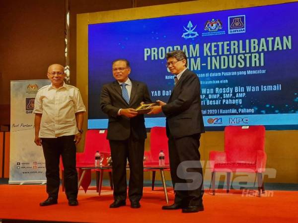 Wan Rosdy (tengah) menerima cenderahati daripada Ahmad Fadzil dalam program Keterlibatan Sirim- Industri di Hotel Zenith hari ini.