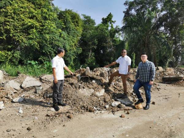 David (dua dari kanan) menunjukkan sisa buangan yang ditambak di tepi Sungai Juru.