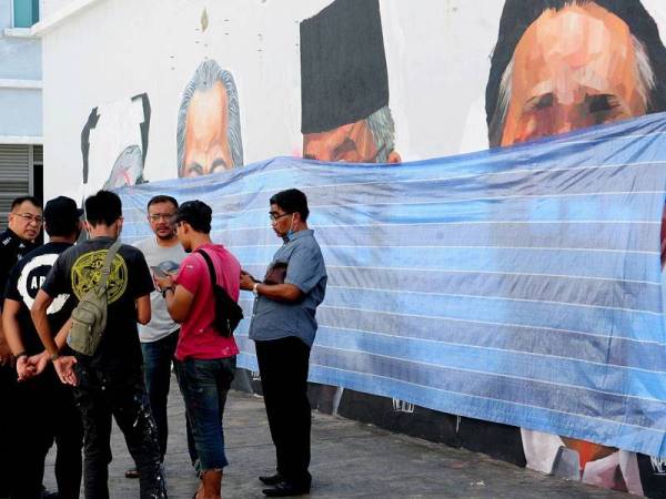 Pelukis bersama polis sedang berbincang susulan mural dan potret lukisan pemimpin negara diconteng di Taman Cahaya Alam. - Foto Bernama