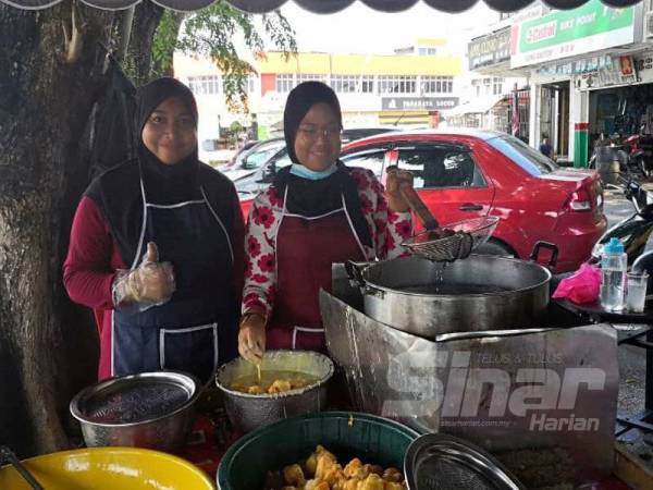 Siti Nurhidayah (kiri) bersama Nor Farhana mula berniaga cempedak goreng di tepi jalan di Pekan Sabak.