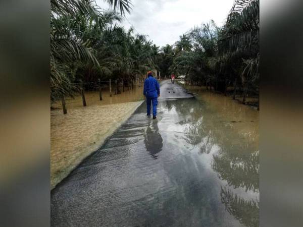 Seorang anggota Angkatan Pertahanan Awam Malaysia ( APM) memantau paras air banjir di Kampung Banggol Rashid Selama.