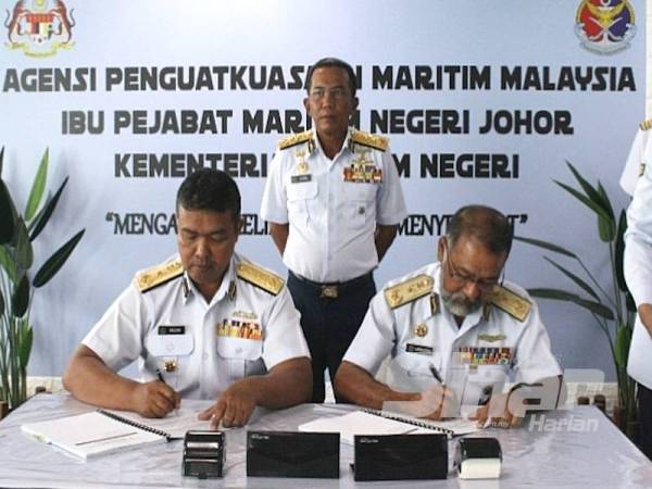 Aminuddin (kanan) menyerahkan tugas kepada Nurul Hizam Zakaria sambil diperhatikan Mohd Zubil (tengah) di Ibu Pejabat Maritim Negeri Johor, Johor Bahru hari ini.