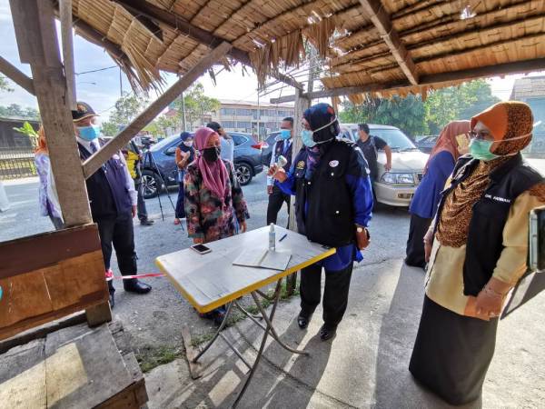 Nor Azimi (dua dari kanan) memeriksa alat penyukat suhu badan di sebuah premis perniagaan di Kuala Terengganu.