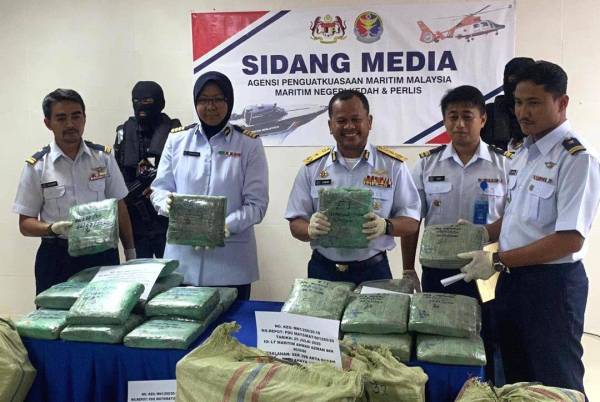 Mohd Zawawi (tengah) menunjukkan bungkusan disyaki ganja dalam enam guni besar yang dirampas dalam operasi terbabit. -Foto: APMM Kedah/Perlis