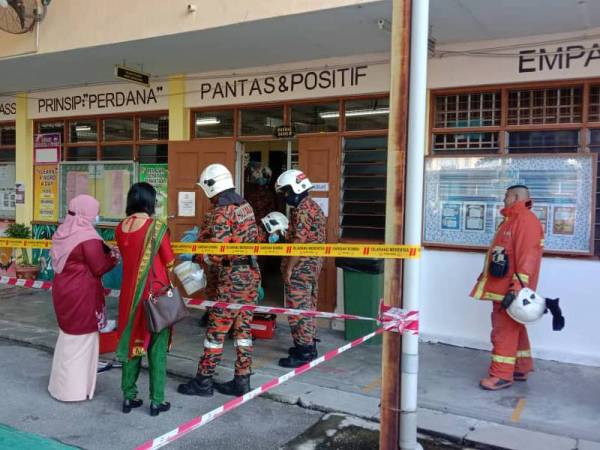 Unit HAZMAT BBP Bayan Baru dan anggota bomba BBP Lebuh Pantai sedang membersihkan bilik makmal sains SMK Hutchings.