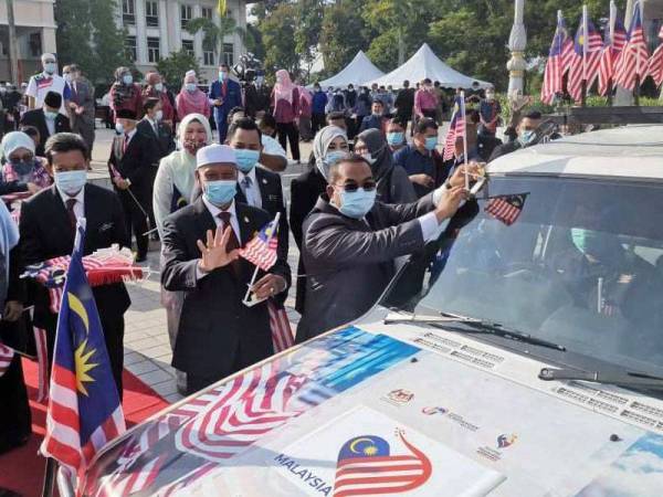 Muhammad Sanusi melekatkan Jalur Gemilang pada kenderaan sebagai simbolik pelancaran sambutan Hari Kebangsaan dan Hari Malaysia di Wisma Darul Aman.