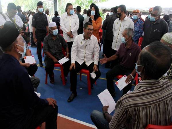 Ahmad Faizal (duduk, tengah) berbual dengan Jamaludin Mohd Nor, 67, (dua dari kanan) penerima Hak Milik dan Notis 5A bagi Rancangan Perkampungan Tersusun (RPT) dan Rancangan Pertanian Berkelompok (RPB) Daerah Kampar pada majlis penyampaian di Pejabat Daerah Kampar hari ini. - Foto Bernama