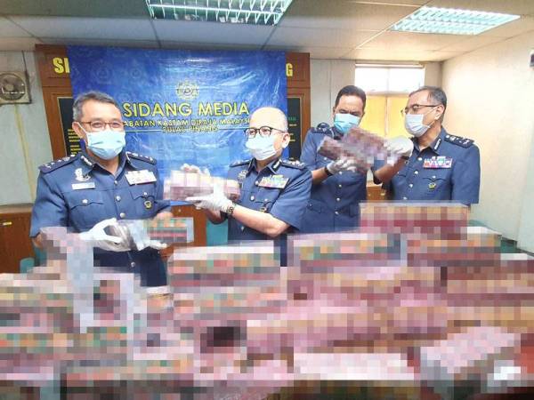 Johari (tengah) menunjukkan rokok putih yang dirampas pada sidang akhbar di Kompleks Pencegah Negeri, Perai hari ini.