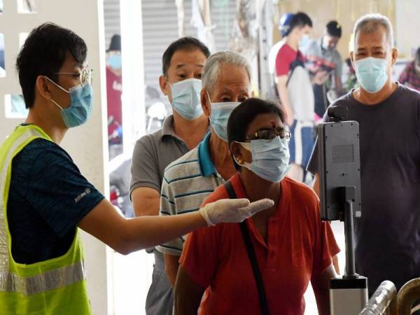 Petugas Pasar Besar Seremban memastikan setiap pelanggan diambil suhu badan dan memakai pelitup separuh muka sebelum memasuki premis berkenaan hari ini. - Foto Bernama