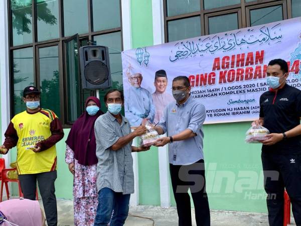 Takiyuddin (dua dari kanan) menyerahkan daging korban kepada salah seorang penerima di Kota Bharu hari ini.