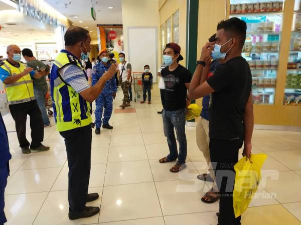 Mohamad Noor melakukan pemeriksaan ke atas pengunjung sebuah pusat beli-belah di sini bagi memastikan mereka patuh arahan pemakaian pelitup muka. 