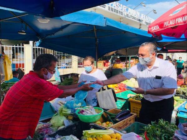 Jagdeep menyerahkan pelitup muka kepada peniaga ketika melawat Pasar Awam Jelutong pagi tadi.