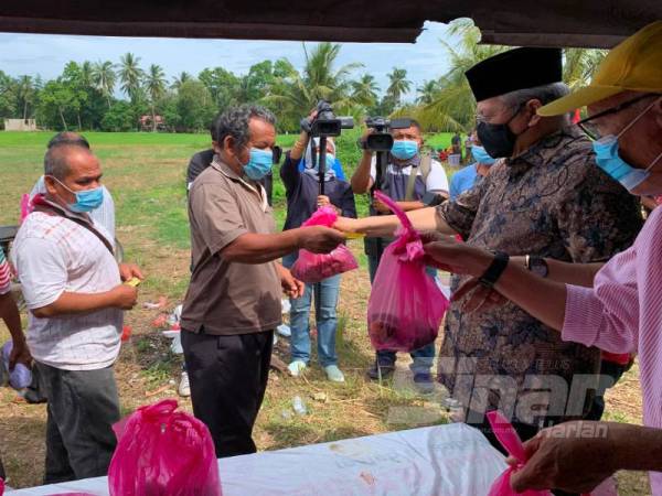 Annuar (dua dari kanan) menyerahkan daging korban kepada penduduk Parlimen Ketereh di Kampung Belukar Luas, Kota Bharu hari ini.