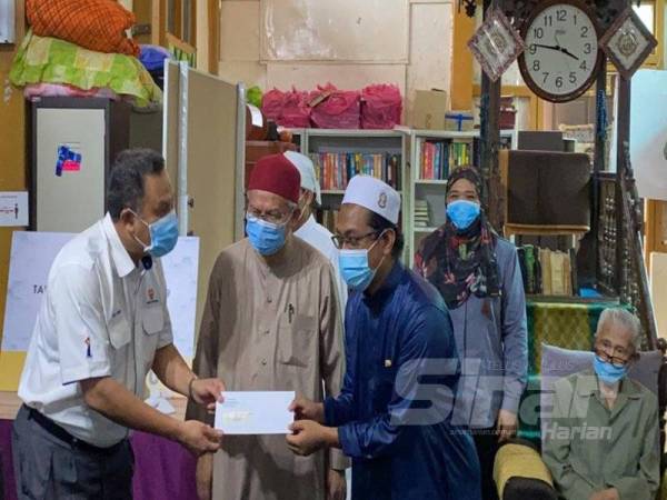 Zulkifli (tengah) menyaksikan sumbangan yang diberikan oleh wakil TNB kepada wakil Maahad Tahfiz Al-Quran Masjid Lama di Lambor Kanan, Seri Iskandar hari ini.