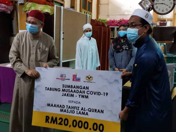 Zulkifli (kiri) menyampaikan sumbangan kepada wakil Maahad Maahad Tahfiz al-Quran Masjid Lama di Seri Iskandar, Parit hari ini.