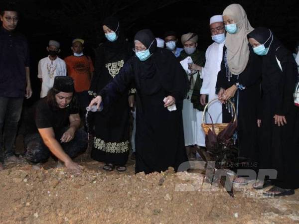 Sharifah Nooraiya menyiram kubur Allahyarham Datuk Abdul Jalil Ali dengan air mawar sambil diperhatikan anak dan saudara-mara.