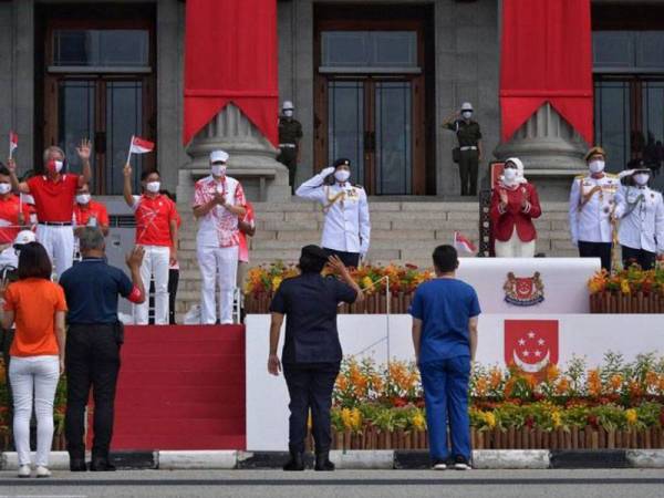 Presiden Singapura, Halimah Yacob (kanan) dan Perdana Menteri Singapura, Lee Hsien Loong (memakai topi putih) bersama ahli Parlimen lain memberi tepukan kepada petugas barisan hadapan ketika acara perbarisan di Padang pagi tadi. - Foto ST