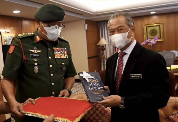 Muhyiddin (kanan) melihat cenderahati yang disampaikan oleh Panglima Tentera Darat (PTD) Jen Datuk Zamrose Mohd Zain ketika menerima kunjungan hormat di Bangunan Parlimen hari ini. -Foto Bernama