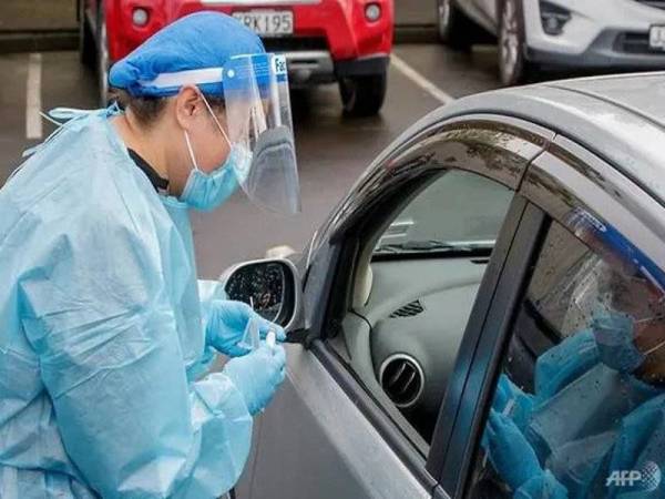 Seorang pekerja kesihatan melakukan ujian Covid-19 terhadap seorang pemandu kereta di sebuah pusat ujian pandemik itu di pinggir Northcote, Auckland. - AFP