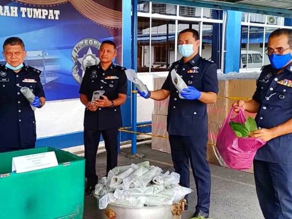 Ab Rashid (kiri) menunjukkan air dan daun ketum yang dirampas dalam serbuan berasingan di sekitar Wakaf Bharu menerusi Op Tapis Bersepadu.