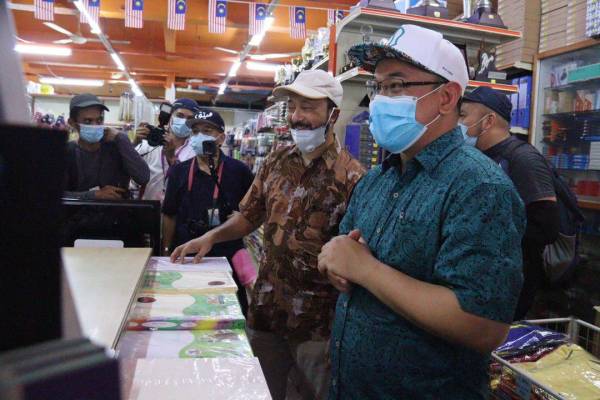 Amir Khusyairi (kanan) bersama Mukhriz ketika sesi bertemu pengundi di Medan Arked Mara, Slim River hari ini.