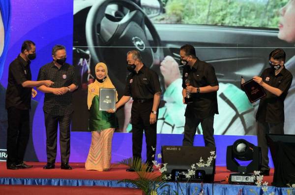 Muhyiddin menyampaikan sijil, trofi dan replika cek sebagai anugerah wira belia Covid-19 kepada orang kurang upaya (OKU) tanpa tangan, Norfarrah Syahirah Shaari dari Perak pada majlis Perasmian Hari Belia Negara 2020 Peringkat Kebangsaan di Pusat Konvensyen Antarabangsa Persada Johor Bahru hari ini. -Foto Bernama