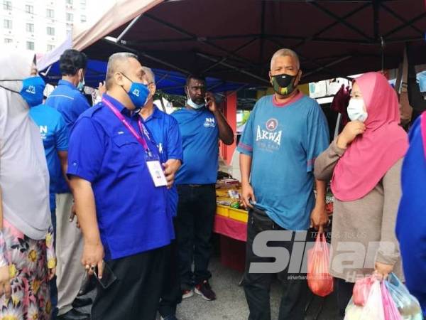 Mohd Zaidi (kiri) bertemu orang ramai ketika berkempen di sekitar Pusat Perniagaan Slim Perdana di Tanjung Malim.