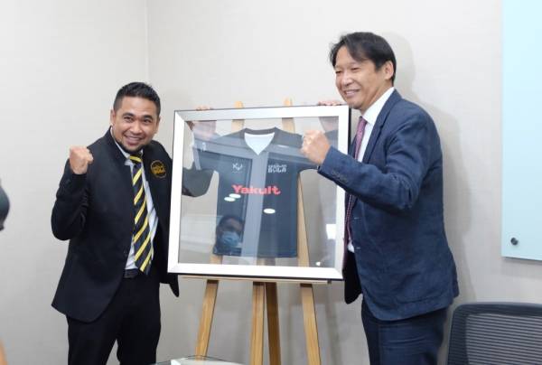 Hiroshi (kanan) dan Muhammad Yazid membuat gimik bertukar jersi selepas menandatangani MoU berkenaan.