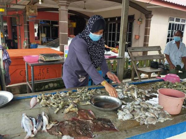 Siti Rahmah menyusun hasil laut sementara menanti pelanggan di kedainya di Kuala Sala di sini hari ini.